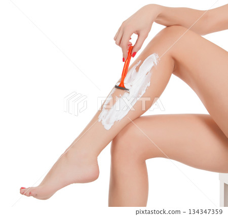 Woman shaving her legs, isolated on white background Woman shaving her legs, isolated on white background 134347359