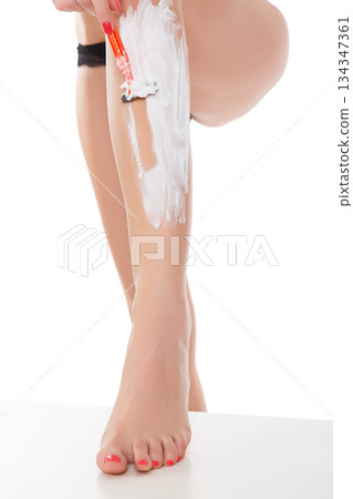 Woman shaving her legs, isolated on white background. 134347361