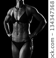 Muscular female body against black background. 134347368
