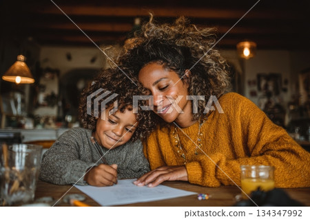 Black mother guiding child in home-school activity 134347992