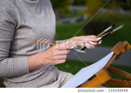 Close-up of artist hands holding painting brushes. Close-up of artist hands holding painting brushes. 134348449