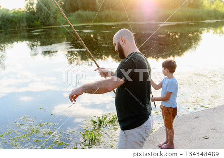 Father and son fishing together at river during sunset Father and son fishing together at river during sunset 134348489