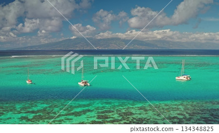 Moorea island landscape showcasing an aerial view of vibrant turquoise and blue lagoon waters, with sailboats moored over a shallow coral reef, and a distant island creating a serene tropical scene Moorea island landscape showcasing an aerial view of vibrant turquoise and blue lagoon waters, with sailboats moored over a shallow coral reef, and a distant island creating a serene tropical scene 134348825