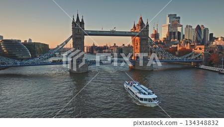 Aerial view of Tower Bridge, one of London's most famous landmarks, City Hall, River Thames and skyscrapers of City of London in background at sunset. Tourist excursion boat. Drone flight Aerial view of Tower Bridge, one of London's most famous landmarks, City Hall, River Thames and skyscrapers of City of London in background at sunset. Tourist excursion boat. Drone flight 134348832