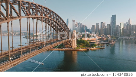 Close up view Sydney Harbor Bridge arch over Sydney Harbor, connecting north shore to bustling central business district, small boat navigating the waters. Architecture and transport. Aerial panorama 134348836