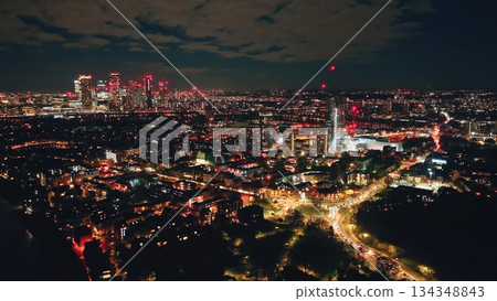 England, London: Breathtaking aerial view of night London city, highlighting the illuminated skyline skyscrapers and vibrant lights of Canary Wharf. Drone flight panorama over modern urban landscape 134348843