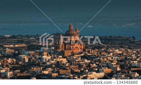 Malta, Comino island: Golden sunset over Church of Saint John the Baptist, Rotunda of Xewkija, Mediterranean Sea, traditional Maltese village landscape in peaceful evening light. Drone flight Malta, Comino island: Golden sunset over Church of Saint John the Baptist, Rotunda of Xewkija, Mediterranean Sea, traditional Maltese village landscape in peaceful evening light. Drone flight 134348860