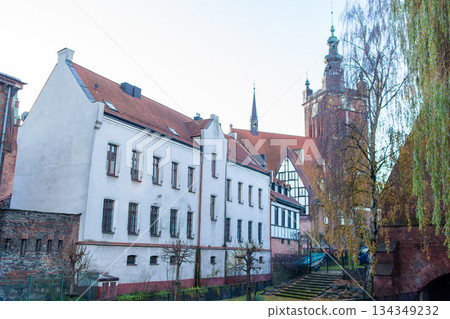 Historic building and tower near a river in a city with trees in winter 134349232