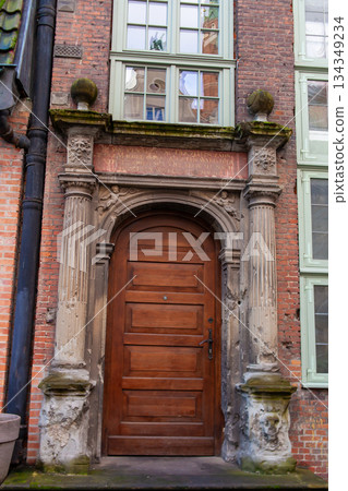 Historic wooden door with stone columns in a city building on a sunny day 134349234