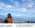 Woman Using Smartphone with Panoramic View of Snowy Himalayan Mountains in Background 134350057