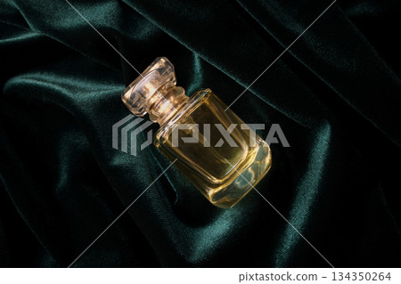 Fragrance bottle with faceted cap resting on luxurious emerald green velvet Fragrance bottle with faceted cap resting on luxurious emerald green velvet 134350264