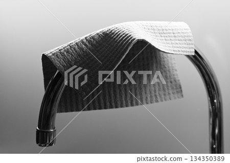 a textured cleaning cloth draped over a curved chrome bar 134350389