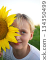 Smiling Child Holding Sunflower in Field 134350499