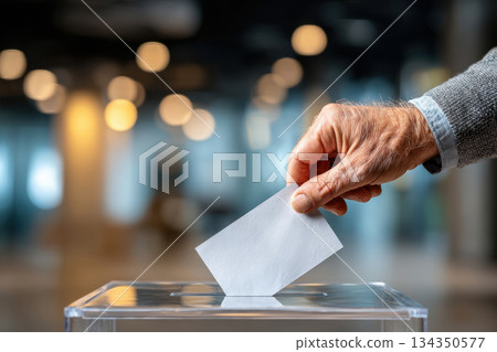 Hand placing paper ballot into transparent voting box Hand placing paper ballot into transparent voting box 134350577