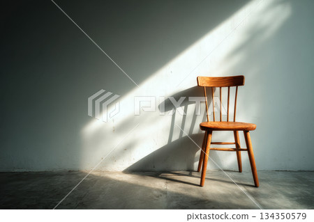 Empty wooden chair against wall with sunlight and shadow indoors Empty wooden chair against wall with sunlight and shadow indoors 134350579