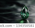 Emerald gemstone on black reflective surface 134350581