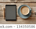 Digital tablet with stylus and cup of coffee on wooden table 134350586
