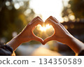 Hands forming heart shape with sunlight in background 134350589