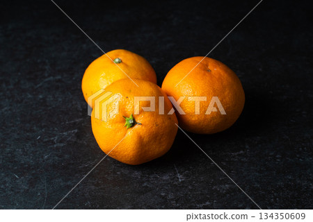 Three mandarins on a black background Three mandarins on a black background 134350609