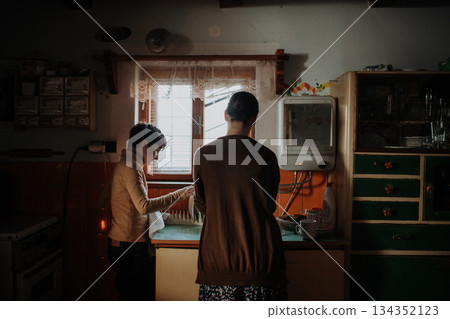 Girl helping mother to wash dishes in an old rural kitchen. Girl helping mother to wash dishes in an old rural kitchen. 134352123