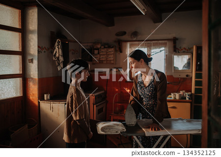 Mother ironing old clothes and fighting with daughter. 134352125