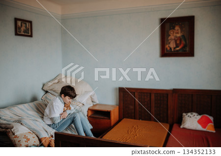 Sad orphan girl sitting alone in bedroom. Poverty concept. 134352133
