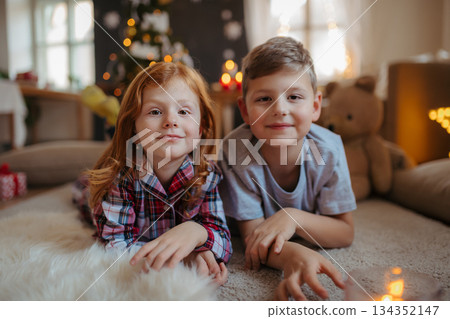 Small girl and boy in pajamas indoors at home at Christmas, playing. Small girl and boy in pajamas indoors at home at Christmas, playing. 134352147