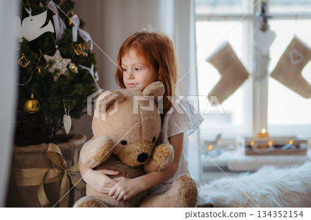 Small girl hugging teddy bear. Christmas mood at home. Small girl hugging teddy bear. Christmas mood at home. 134352154