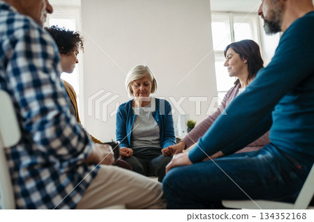 Group of people sitting in a circle and sharing experiences during guided therapeutic session. Group of people sitting in a circle and sharing experiences during guided therapeutic session. 134352168