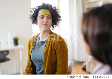 Woman writing her problem on sticky note during group therapy session. 134352174