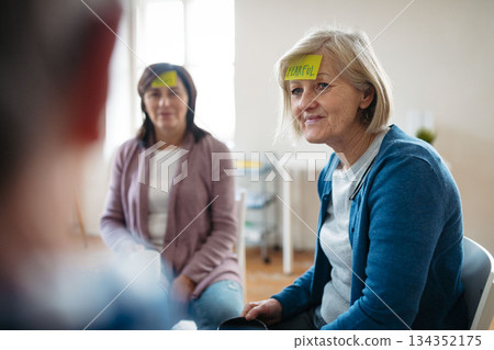 Senior woman identifying emotions during group therapy session. Senior woman identifying emotions during group therapy session. 134352175