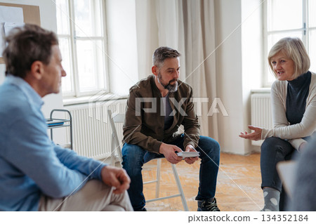 Group of people sitting in a circle and sharing experiences during guided therapeutic session. Group of people sitting in a circle and sharing experiences during guided therapeutic session. 134352184