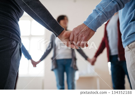 Group of people standing in a circle and holding hands during therapy. 134352188