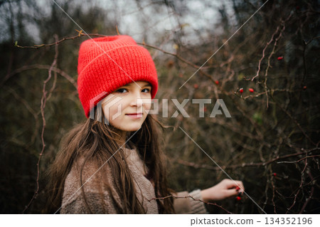 Preteen girl on walk nature wearing red hat. 134352196