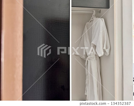 A clean white waffle bathrobe is hanging on a hanger in the hotel closet. High quality photo A clean white waffle bathrobe is hanging on a hanger in the hotel closet. High quality photo 134352387