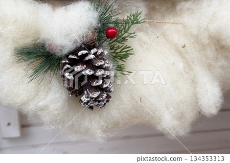 Christmas pinecone decoration with artificial snow on wooden background. Winter holiday symbolism, natural ornament, seasonal coziness, handmade festive atmosphere and rustic Christmas mood Christmas pinecone decoration with artificial snow on wooden background. Winter holiday symbolism, natural ornament, seasonal coziness, handmade festive atmosphere and rustic Christmas mood 134353313