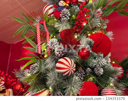 Detailed view of Christmas tree with red ornaments and pinecones. Seasonal decoration, festive texture and classic holiday styling. Detailed view of Christmas tree with red ornaments and pinecones. Seasonal decoration, festive texture and classic holiday styling. 134353370