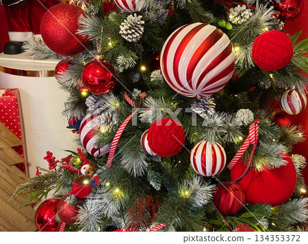 Red and white Christmas ornaments on decorated fir tree. Holiday atmosphere, festive tradition, winter celebration and cozy seasonal decor. 134353372