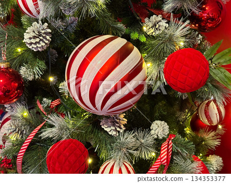 Red and white Christmas ornaments on decorated fir tree. Holiday atmosphere, festive tradition, winter celebration and cozy seasonal decor. Red and white Christmas ornaments on decorated fir tree. Holiday atmosphere, festive tradition, winter celebration and cozy seasonal decor. 134353377