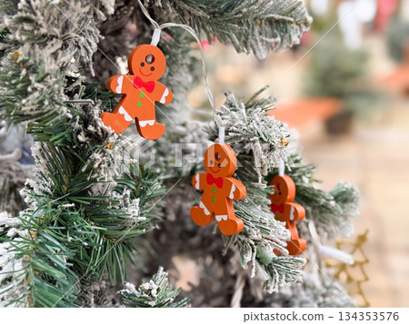 Gingerbread figure ornament on snow covered Christmas tree. Festive winter decor, playful detail and seasonal holiday atmosphere 134353576