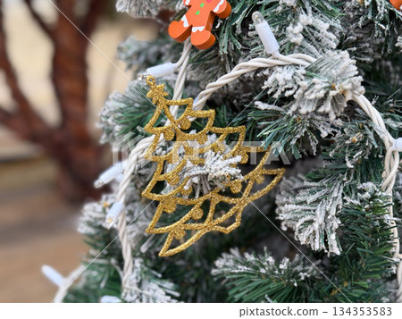 Gold Christmas tree ornament on snowy artificial branches. Elegant holiday decoration, winter texture and festive close up detail 134353583