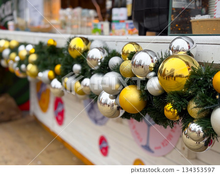 Christmas garland with gold and silver baubles on cafe counter. Festive street decor, winter atmosphere and seasonal holiday styling Christmas garland with gold and silver baubles on cafe counter. Festive street decor, winter atmosphere and seasonal holiday styling 134353597