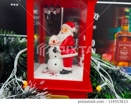 Santa Claus and snowman figurines inside red lantern decoration. Traditional Christmas symbols, festive decor and winter holiday atmosphere Santa Claus and snowman figurines inside red lantern decoration. Traditional Christmas symbols, festive decor and winter holiday atmosphere 134353613