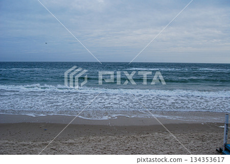 Sea waves crashing on a sandy shore under a cloudy sky. Waves crashing on a sandy shore under a cloudy sky, as seen from the railing on a beach in Odessa. 134353617