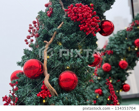 Christmas tree decorated with glossy red balls and natural branches in festive environment. Holiday decor detail, winter celebration and traditional seasonal atmosphere. Christmas tree decorated with glossy red balls and natural branches in festive environment. Holiday decor detail, winter celebration and traditional seasonal atmosphere. 134353704