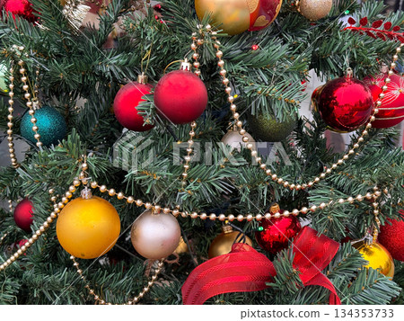 Detailed view of Christmas ornaments and garlands on decorated fir tree. Holiday decoration, winter celebration, festive atmosphere and traditional seasonal styling. Detailed view of Christmas ornaments and garlands on decorated fir tree. Holiday decoration, winter celebration, festive atmosphere and traditional seasonal styling. 134353733
