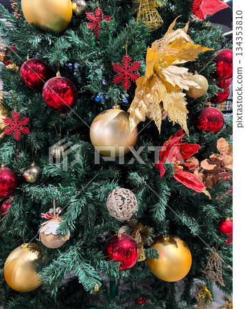 Decorated christmas tree with red and gold ornaments in festive interior. Classic holiday styling, seasonal decoration, traditional winter celebration and warm festive atmosphere Decorated christmas tree with red and gold ornaments in festive interior. Classic holiday styling, seasonal decoration, traditional winter celebration and warm festive atmosphere 134353810