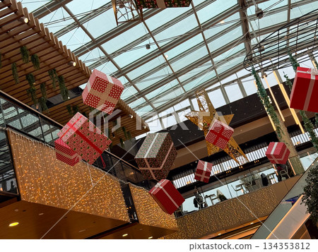 Hanging christmas gift boxes installation inside modern shopping mall. Festive holiday decor, seasonal celebration, playful winter design and joyful christmas atmosphere Hanging christmas gift boxes installation inside modern shopping mall. Festive holiday decor, seasonal celebration, playful winter design and joyful christmas atmosphere 134353812