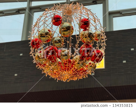 Illuminated christmas ornament sphere suspended indoors. Holiday decor element, seasonal lighting design, festive interior styling and winter celebration concept Illuminated christmas ornament sphere suspended indoors. Holiday decor element, seasonal lighting design, festive interior styling and winter celebration concept 134353815