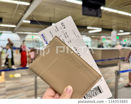 A girl holds her passport and boarding pass in her hand at the international airport A girl holds her passport and boarding pass in her hand at the international airport 134353885